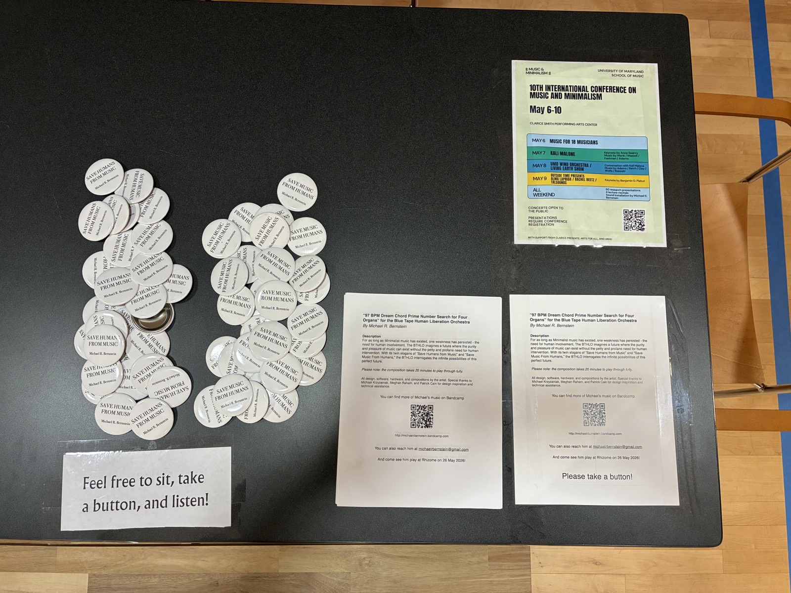 "Save Humans from Music" / "Save Music from Humans" buttons, flyers, and conference poster on a table